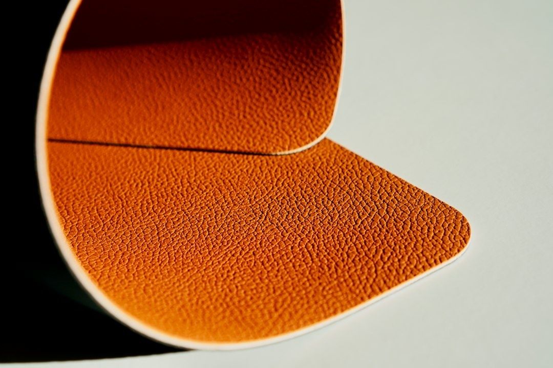 Närbild av orangebrunt läder med tydlig narv och en skarvad kant
