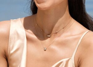 Närbild av två lager halsband mot en ljus, tunn klänning
